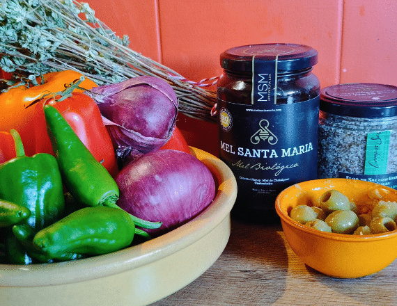 Verse ingrediënten voor Portugese tomatensalade – tomaten, knoflookolijven, ui en pão caseiro