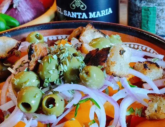 Portugese tomatensalade met olijven en croutons op een zonnig bord – zomers gerecht voor bij de BBQ
